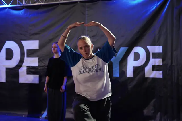 Tanečník s rukami nad hlavou pred bannerom HYPE