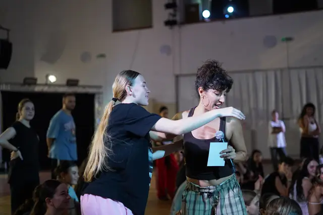 Two dancers dancing close together while others watch
