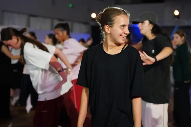 Students smiling and dancing in a daylight-filled hall