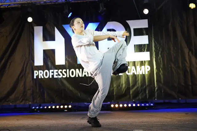 Tanečník v bielom robí floor work pred bannerom HYPE Professional Dance Camp